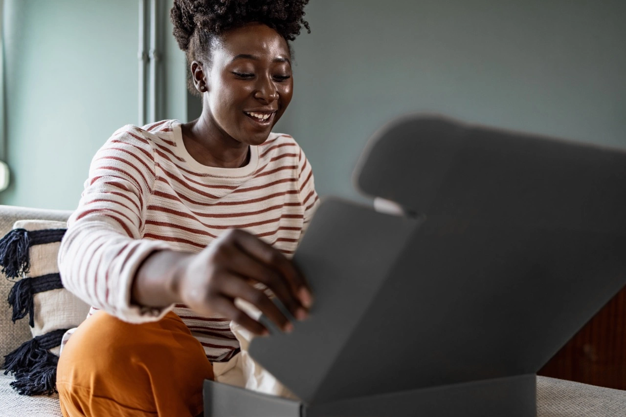 A woman excitedly opens a black gift box